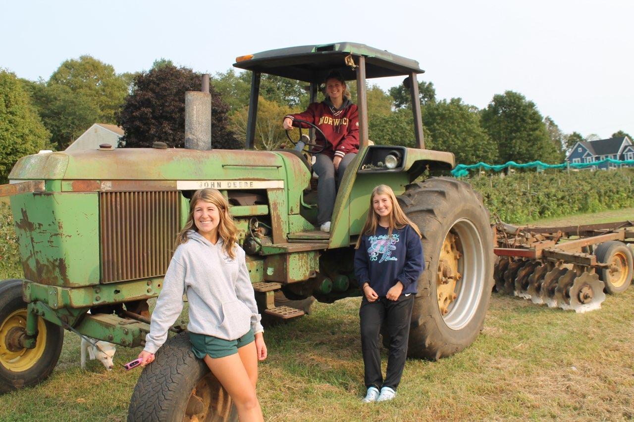 A picture of three women and a green tractor